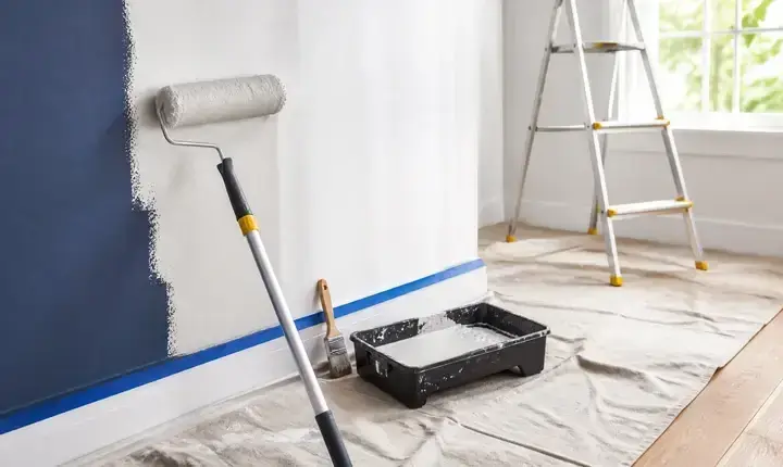 Mise en œuvre peinture intérieure avec rouleau, bac, bâche, ruban et mur en cours